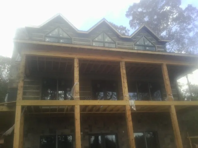Dormers and porch framing on a large log home under construction — Roof Coating work by our crew in Nashville